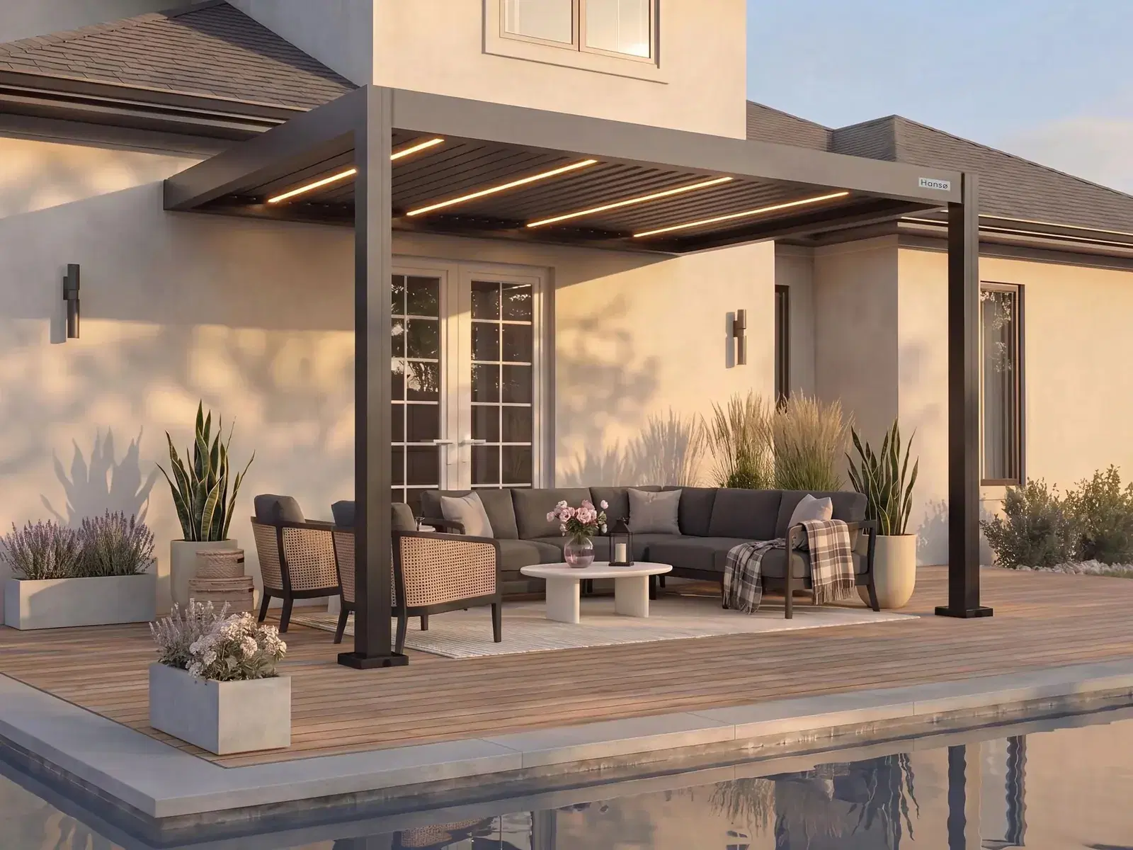 Hansø Apex pergola in dark gray over a patio seating area with its aluminum louvers closed