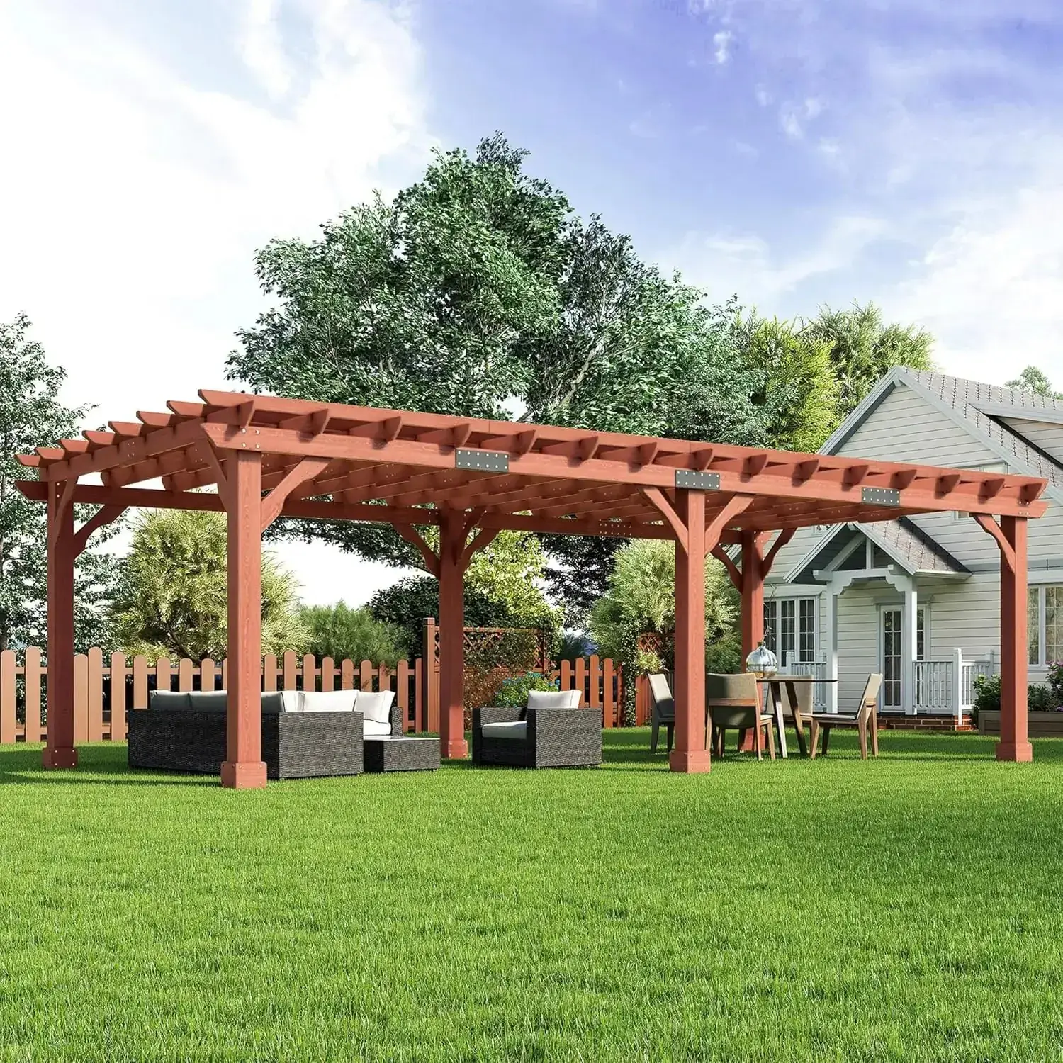 Cedrix 12x24 red-brown cedar pergola over a backyard patio, with a dark wicker sectional sofa, two armchairs and a coffee table on one side and a round dining table with four chairs on the other, a white house and mature trees behind