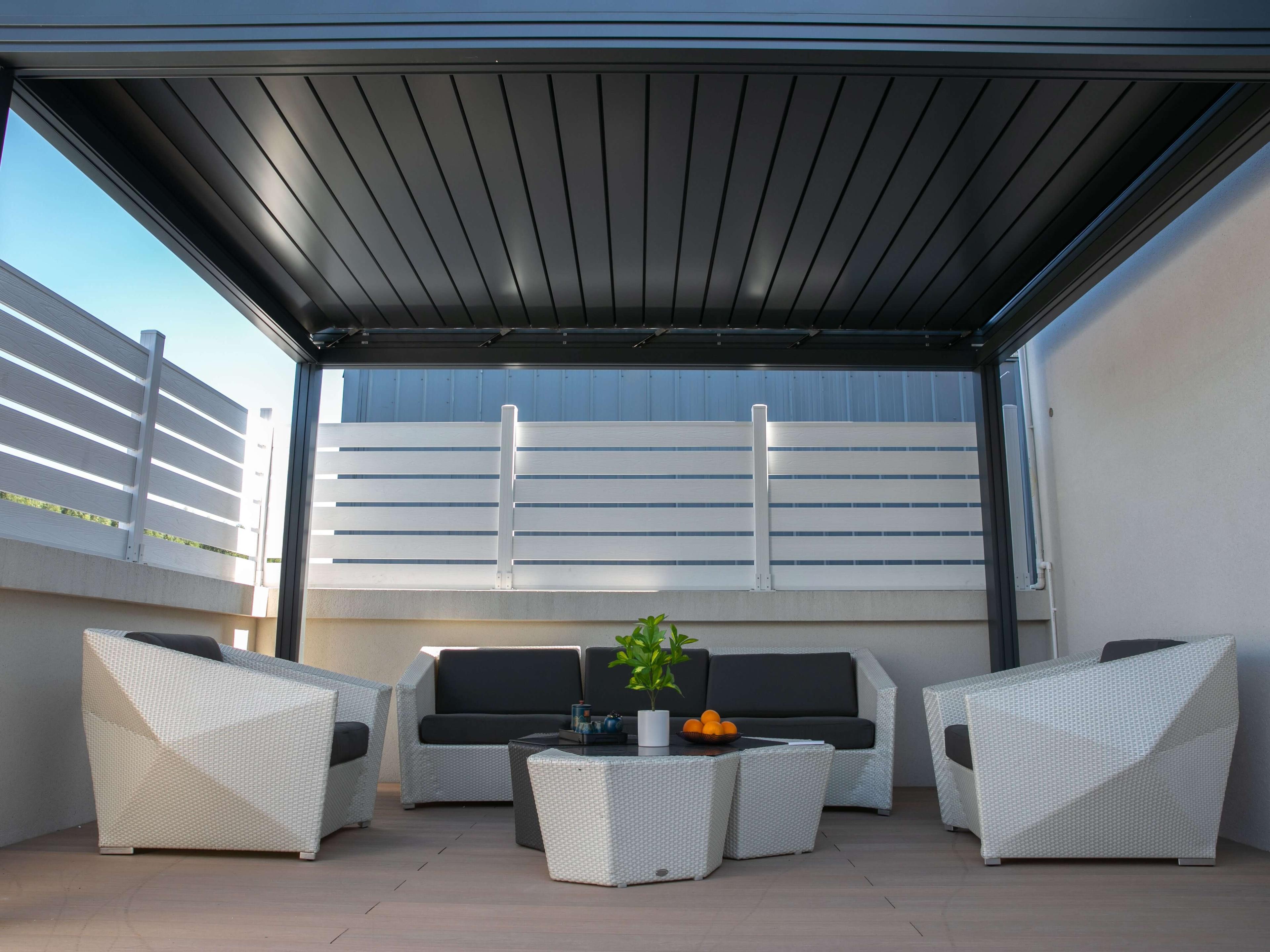 Dark gray Grand Retractable Pergola with the roof closed over a rooftop terrace lounge