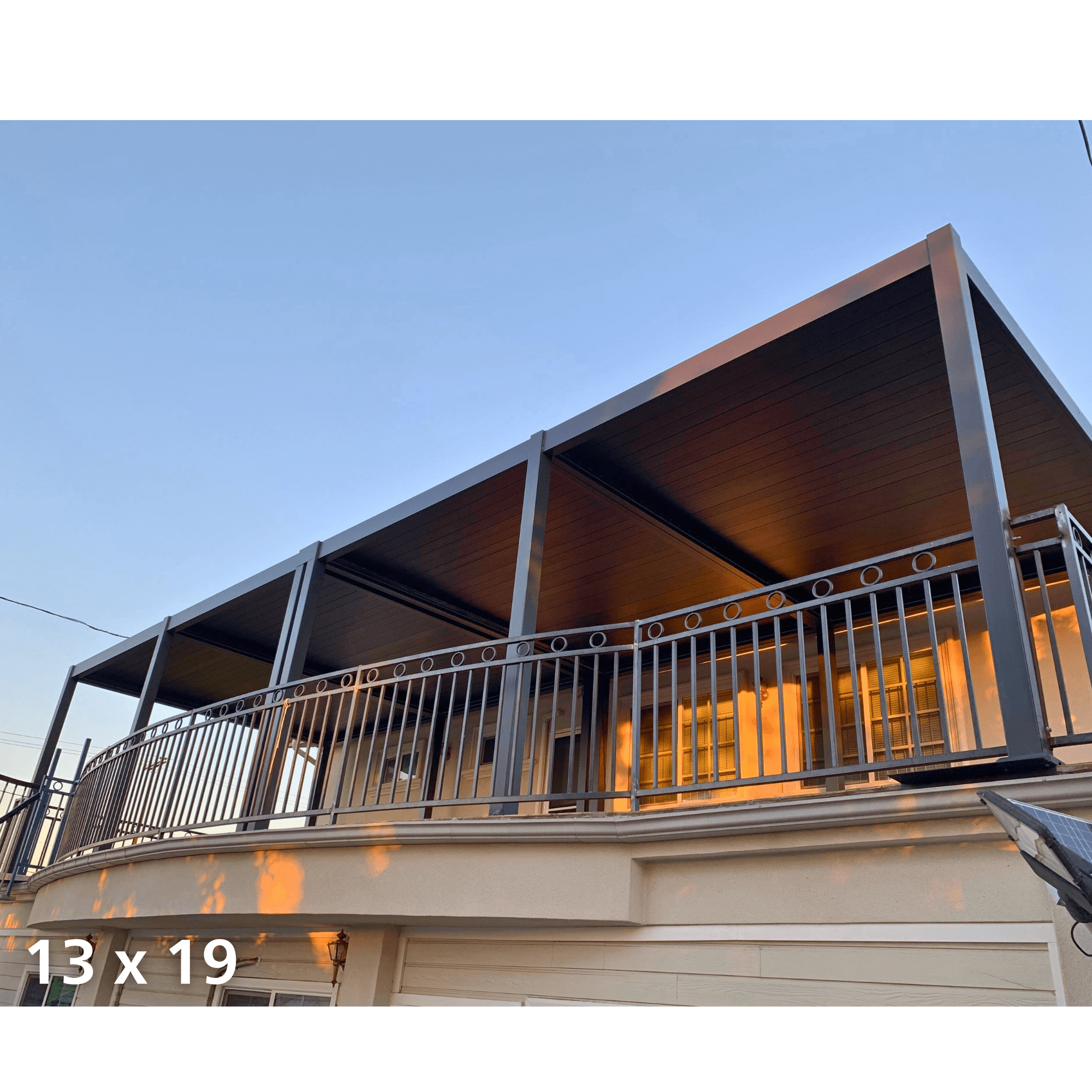 Dark gray Villa Pergola with oak grain louvers installed on a first-floor balcony at sunset