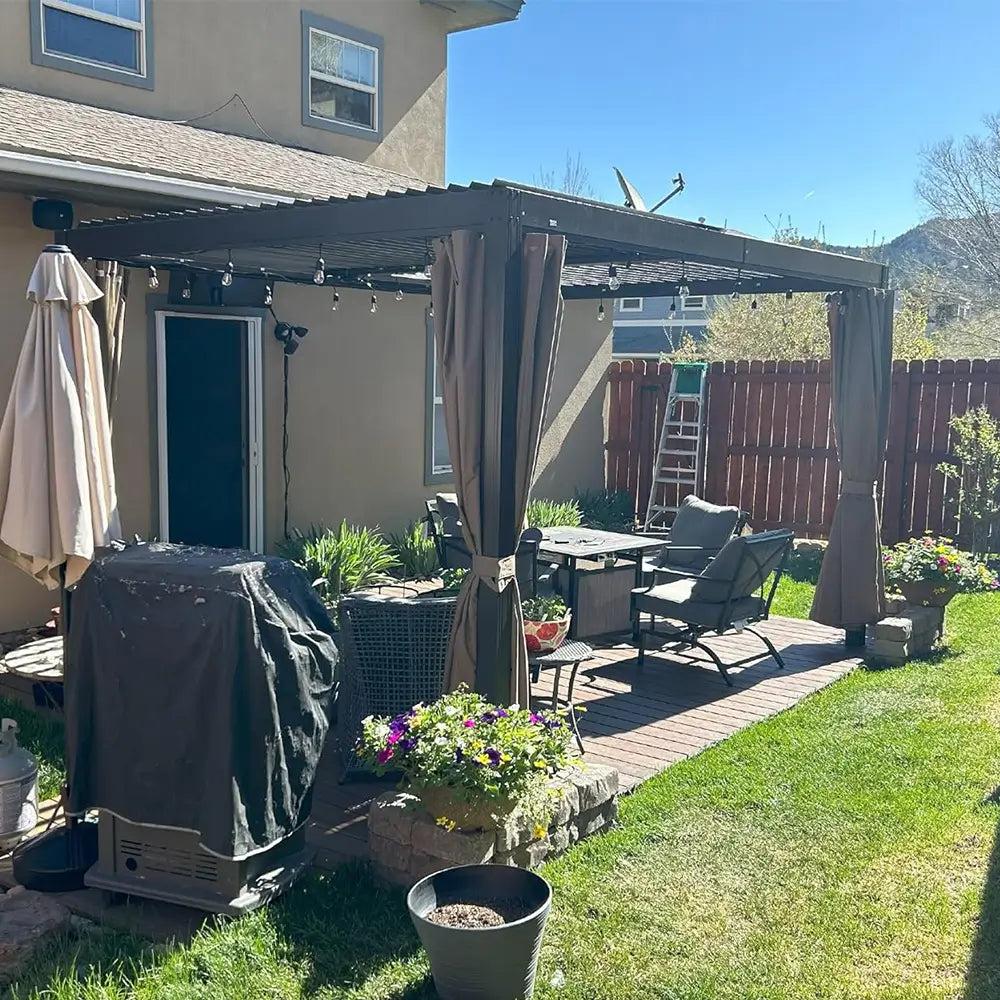 Domi Outdoor Living aluminum louvered pergola with curtains over patio furniture and a covered grill in a backyard