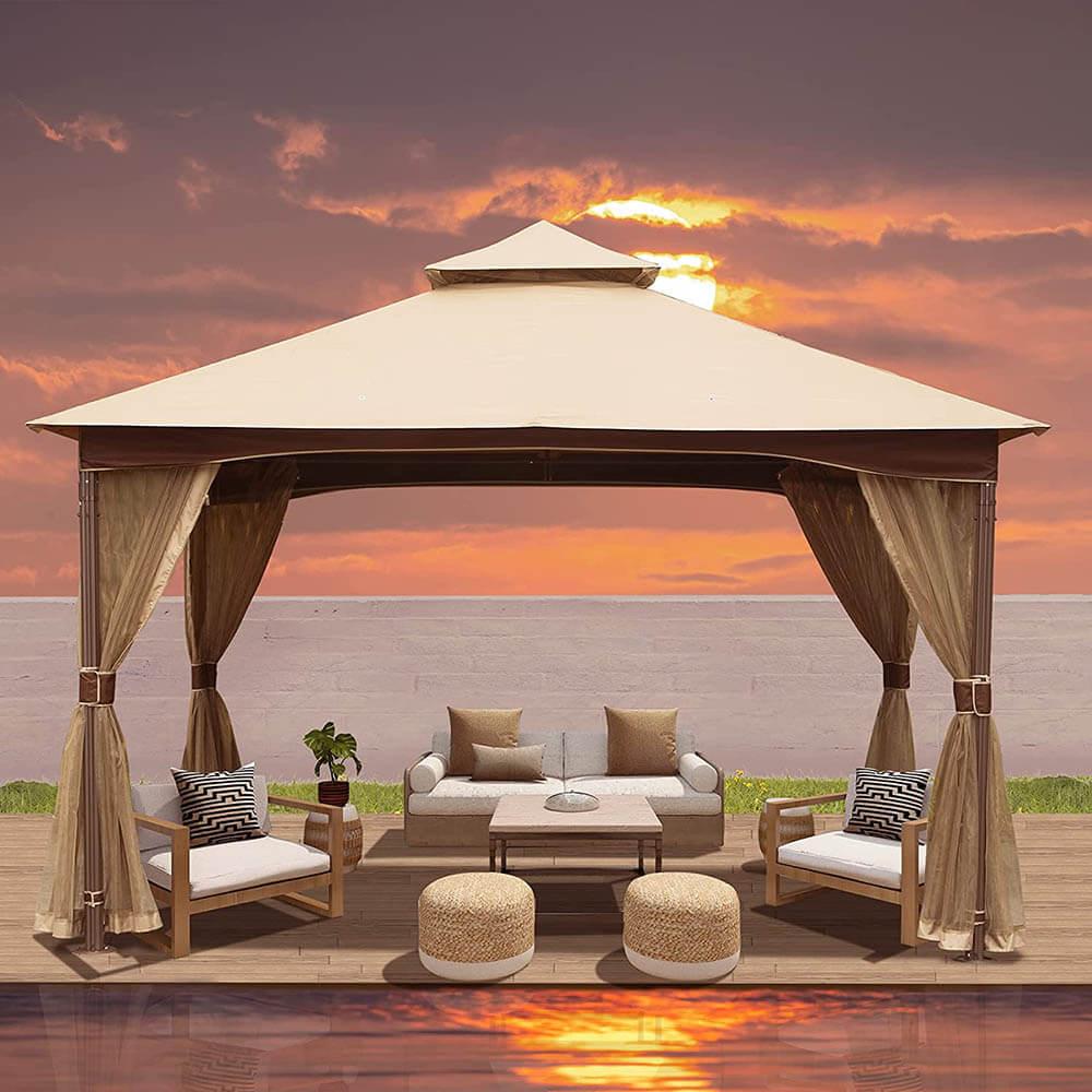 Domi Outdoor Living 10x13 soft double-roof gazebo with a beige fabric roof and curtains over cushioned seating at sunset