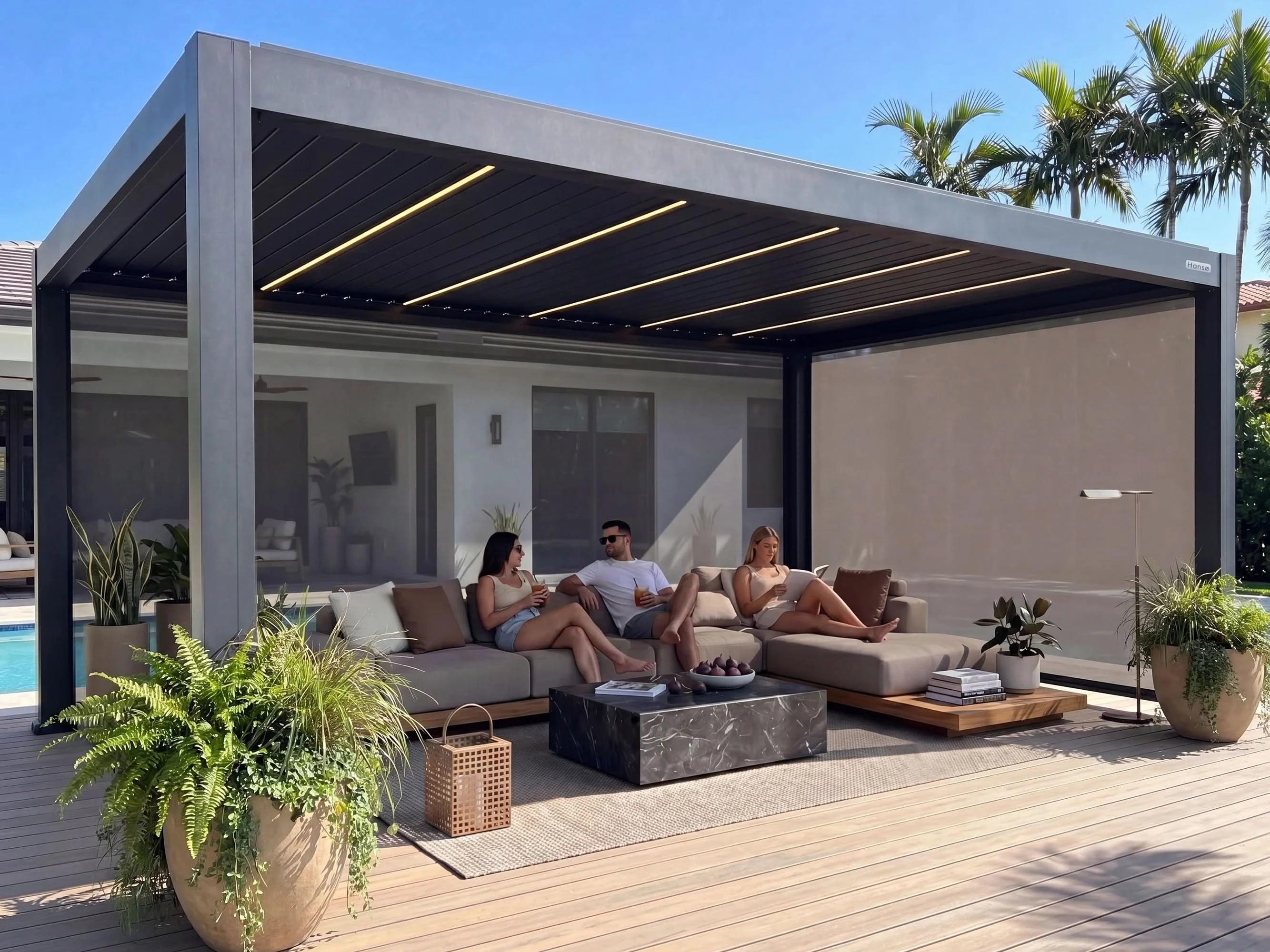 Hansø Apex pergola with a dark gray frame over an outdoor lounge set, louvers open to a blue sky