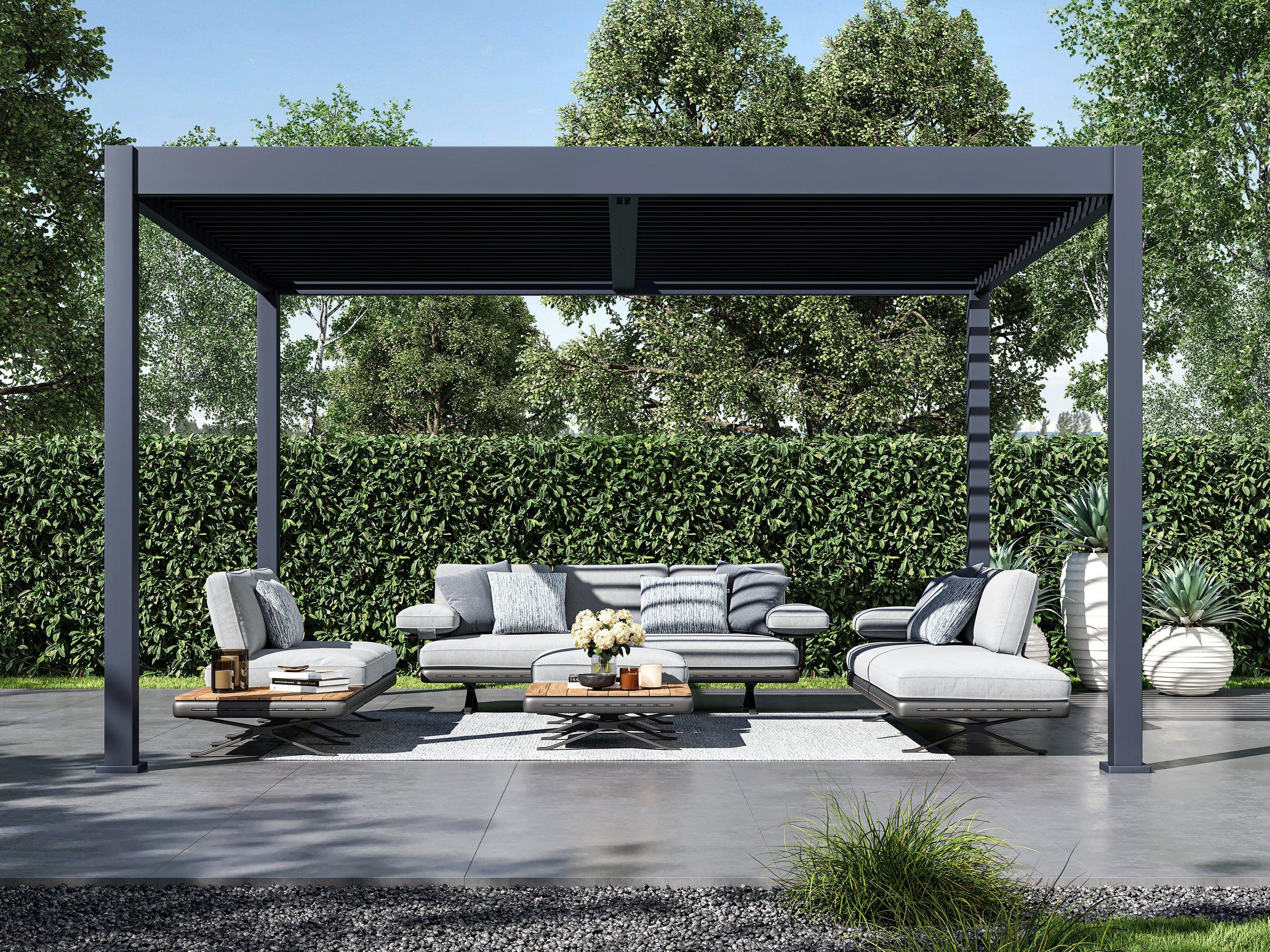 Slate Gray Grand Tuscan louvered pergola seen head-on over a paved garden lounge beside a clipped hedge