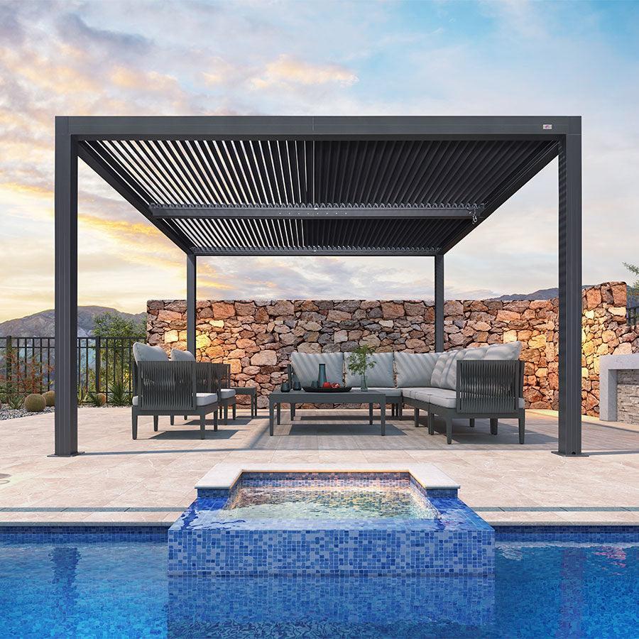 Athena louvered pergola with the louvers closed over a lounge set beside a stone hot tub
