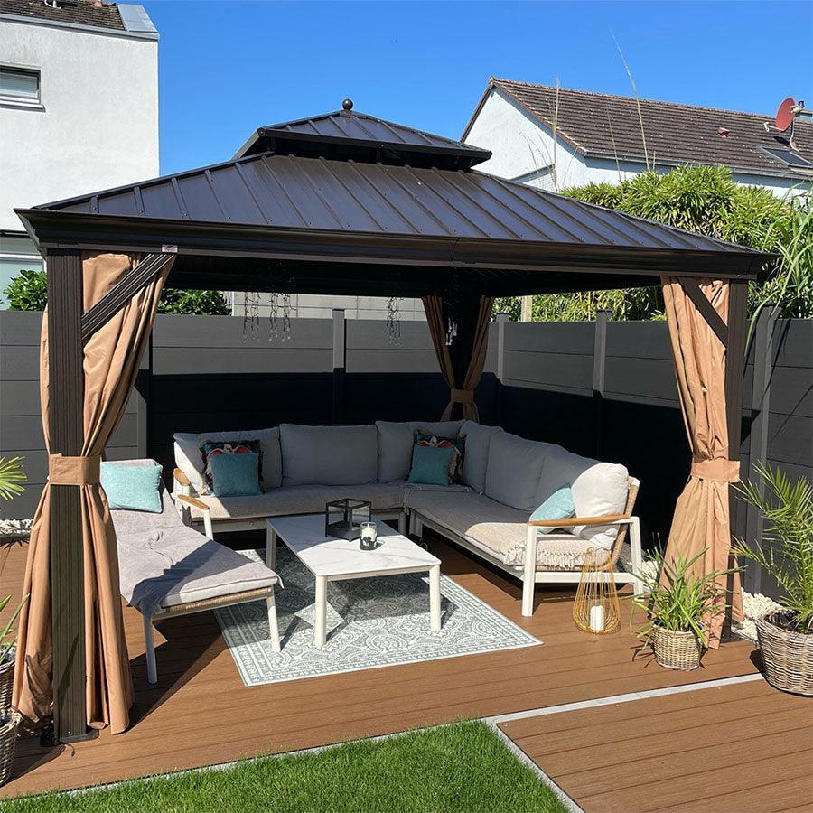 Bronze hardtop gazebo at dusk with curtains drawn back around a patio sofa set