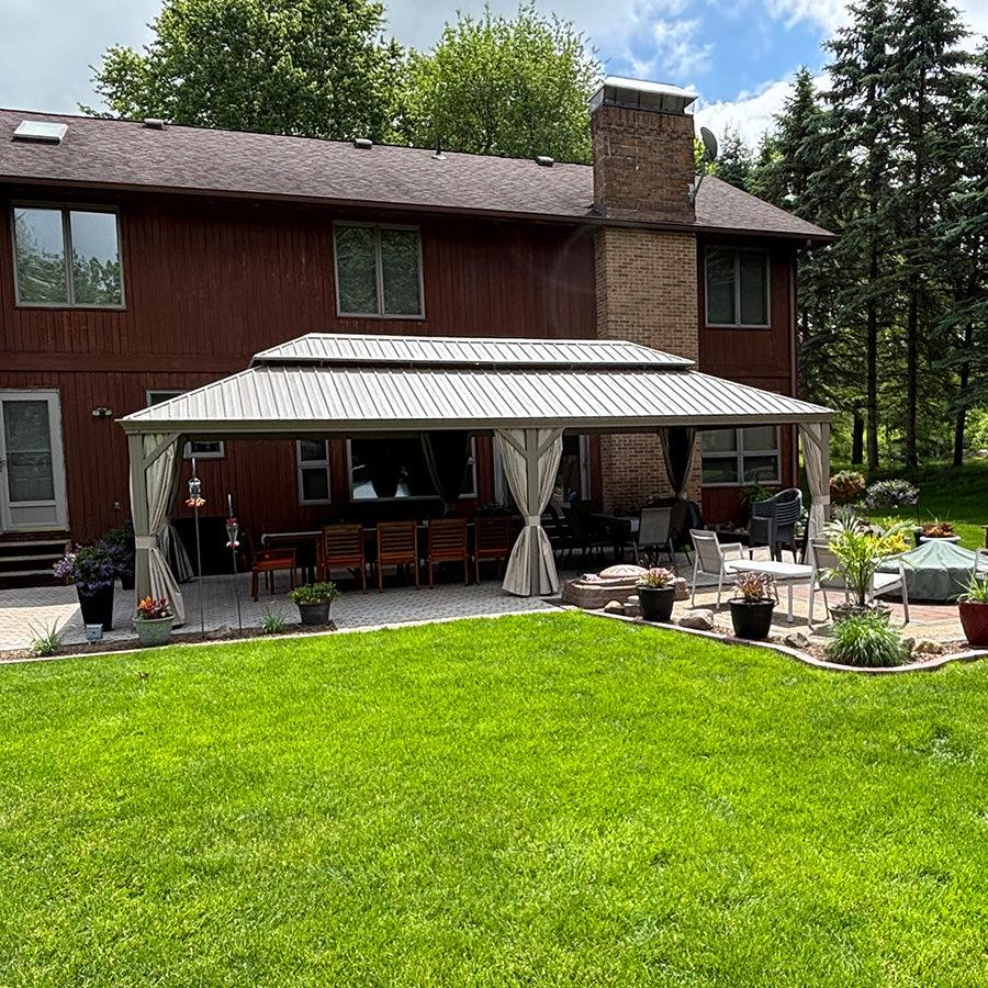 Champagne hardtop gazebo built on a brick house patio with an outdoor seating area