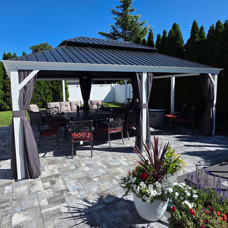 White-post hardtop gazebo on a paver patio with a dining table and potted plants