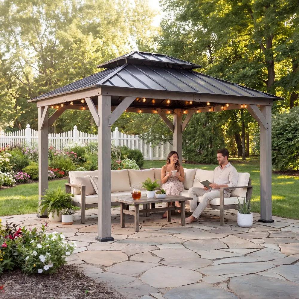 Sunjoy Double-Tier Cedar 10x12 gazebo in driftwood cedar on a flagstone patio, two people seated on a cushioned sofa beneath it