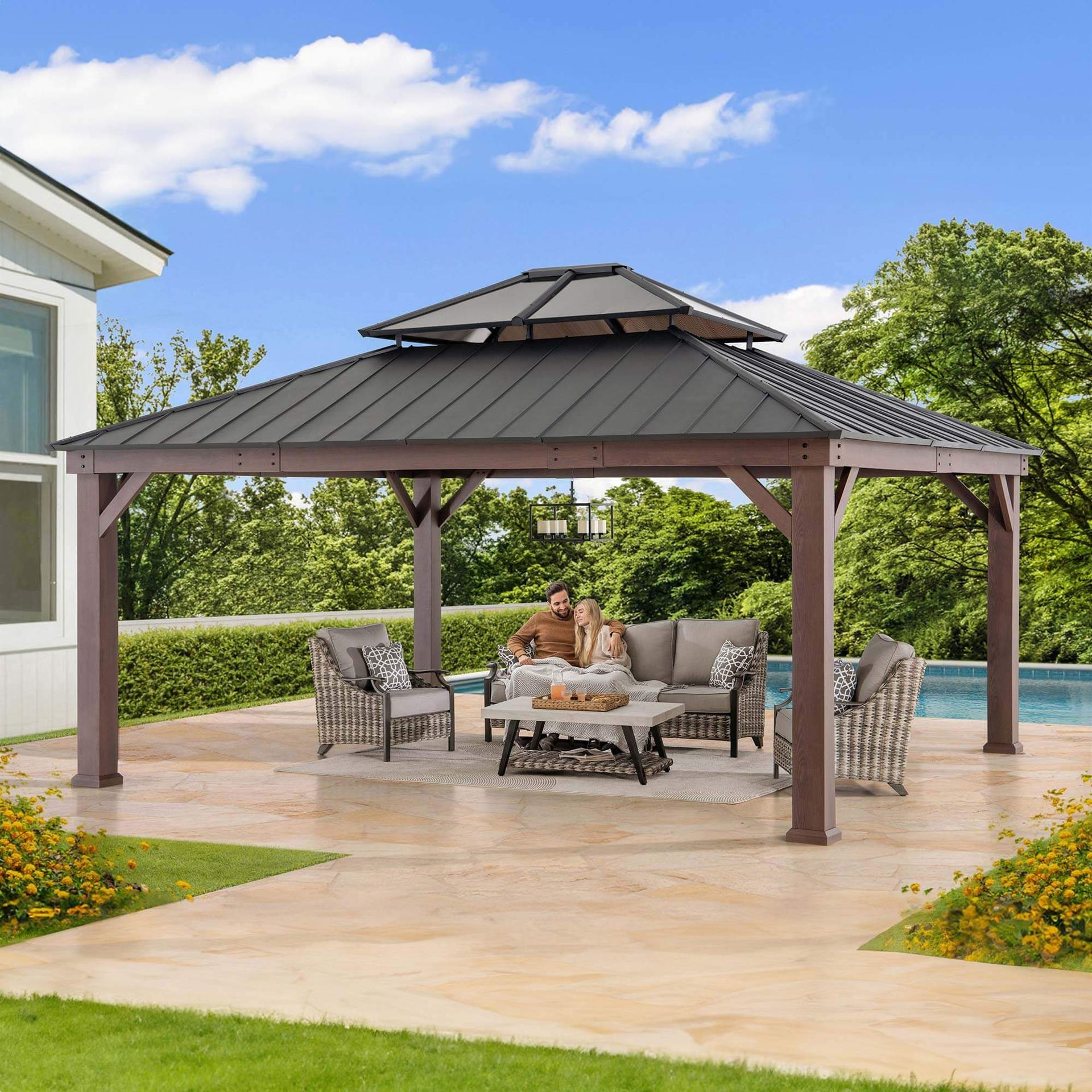 Sunjoy Fenwick hardtop gazebo with a wood-look frame and a double steel roof on a poolside patio, with outdoor sofas underneath