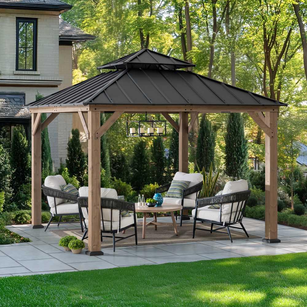 Sunjoy Hampton 11x11 gazebo on a paved patio beside a house, sheltering two armchairs and a sofa