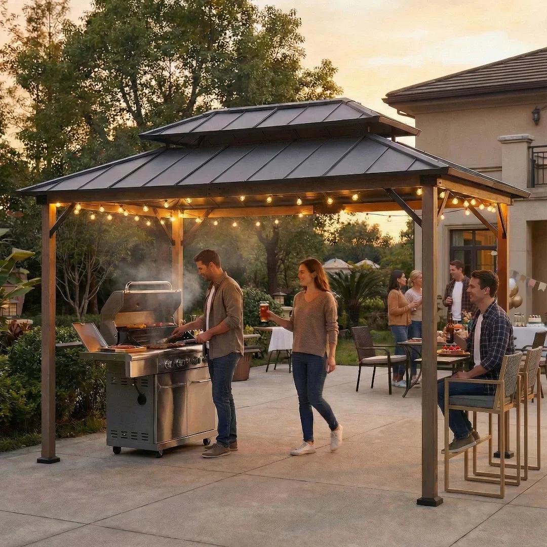 Sunjoy Pro-Grill Performance Station 8x12 on a patio at dusk, string lights lit under the roof and a gas grill in use beneath it