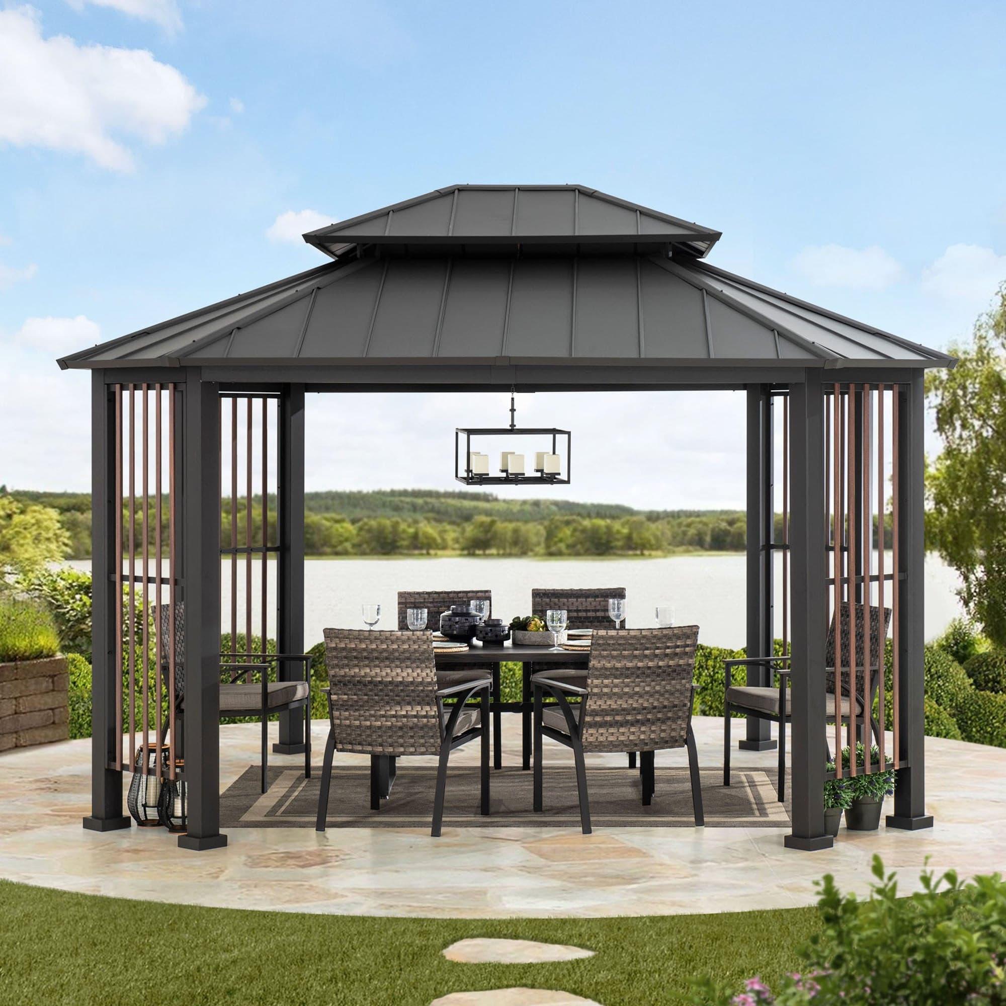 Sunjoy Rockwood octagon hardtop gazebo on a lawn overlooking water, sheltering a rattan dining set with a pendant light hung from the ceiling hook
