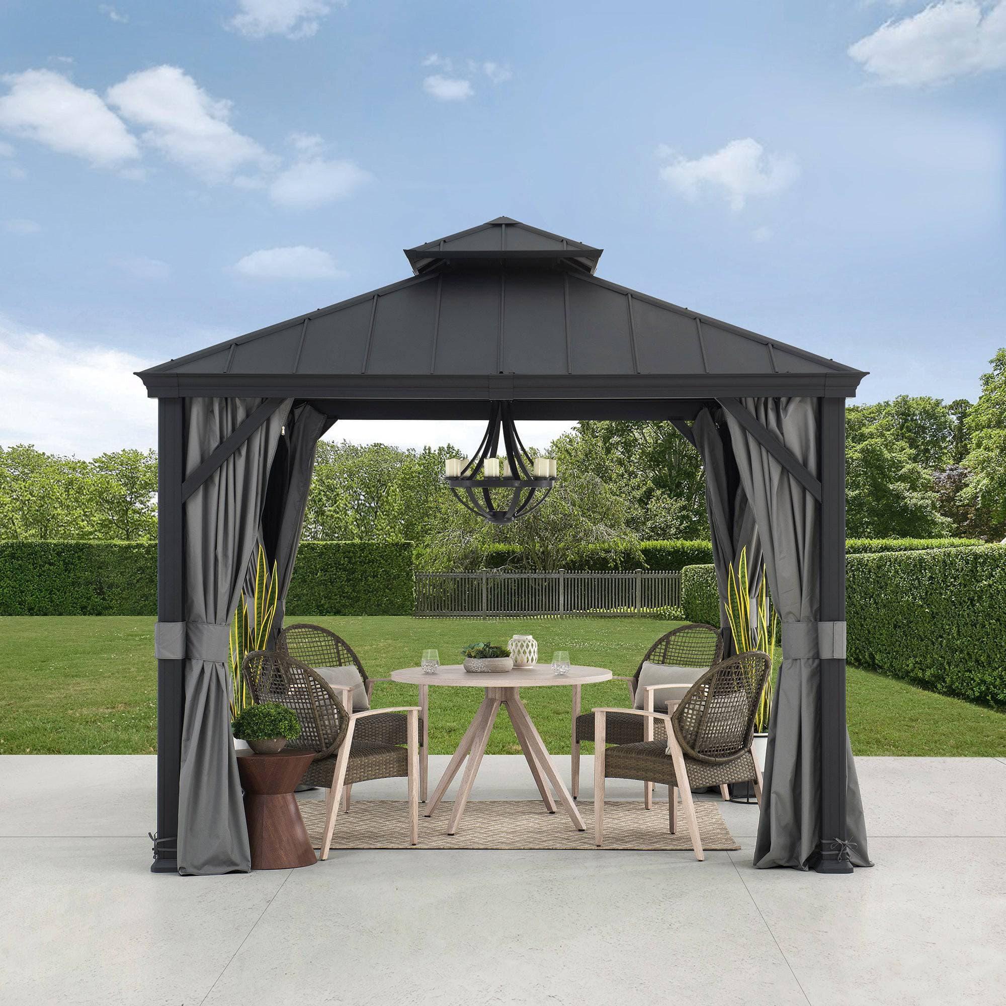 Sunjoy Summit Minimalist 10×10 aluminum gazebo on a paved patio, two-tier steel hardtop roof with grey curtains tied back at each post over a round table and four chairs
