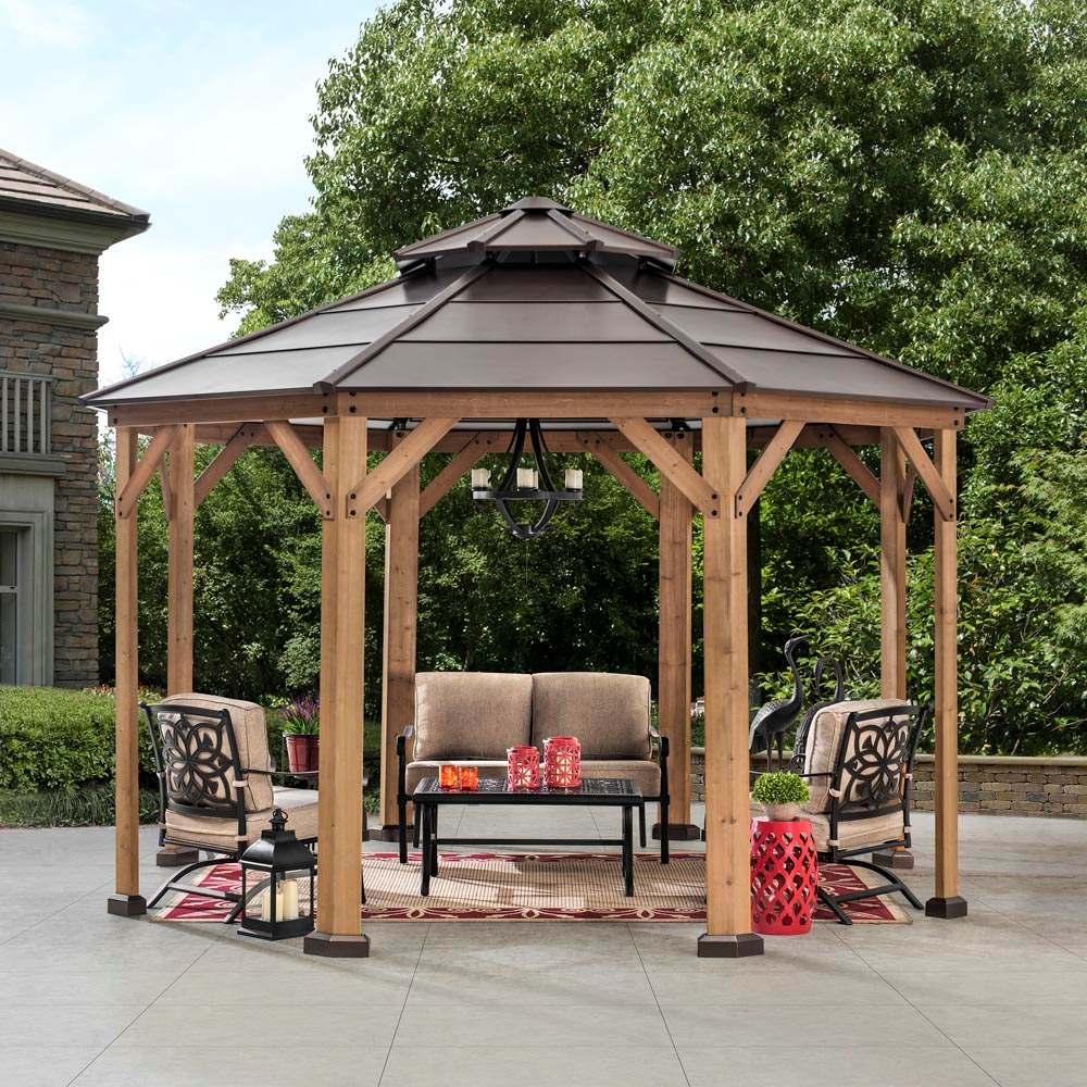 Sunjoy Valerie 13x13 octagon gazebo on a paved patio sheltering a sofa and armchairs on a patterned rug