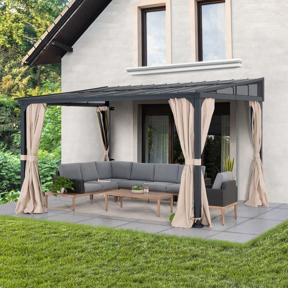 Sunjoy Vista Hardtop Wall-Mounted gazebo 10x12 fitted against a rendered house wall, its roof sloping away over a corner sofa and coffee table on a paved patio