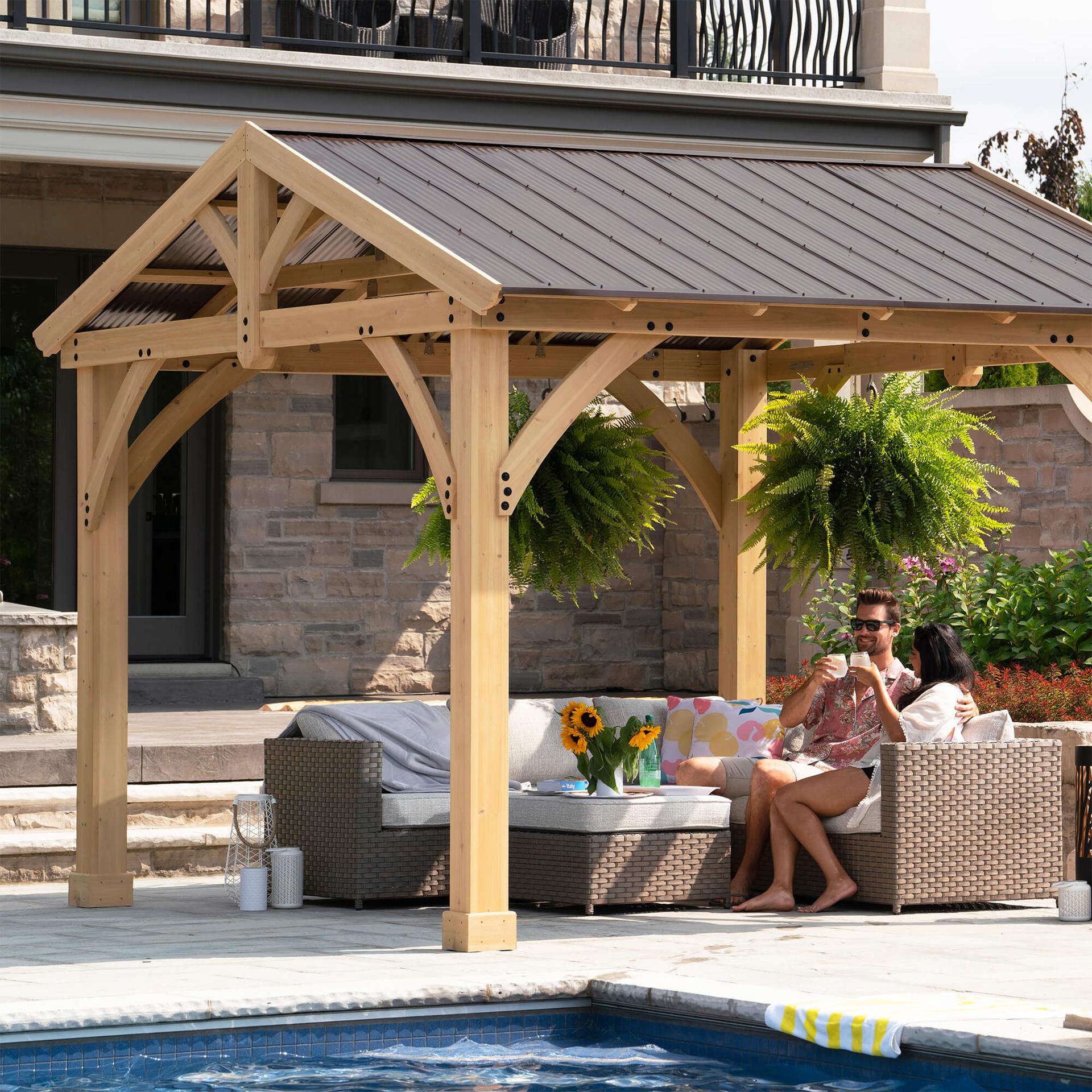 Carolina pavilion beside a pool with hanging plants and a family seated under the roof