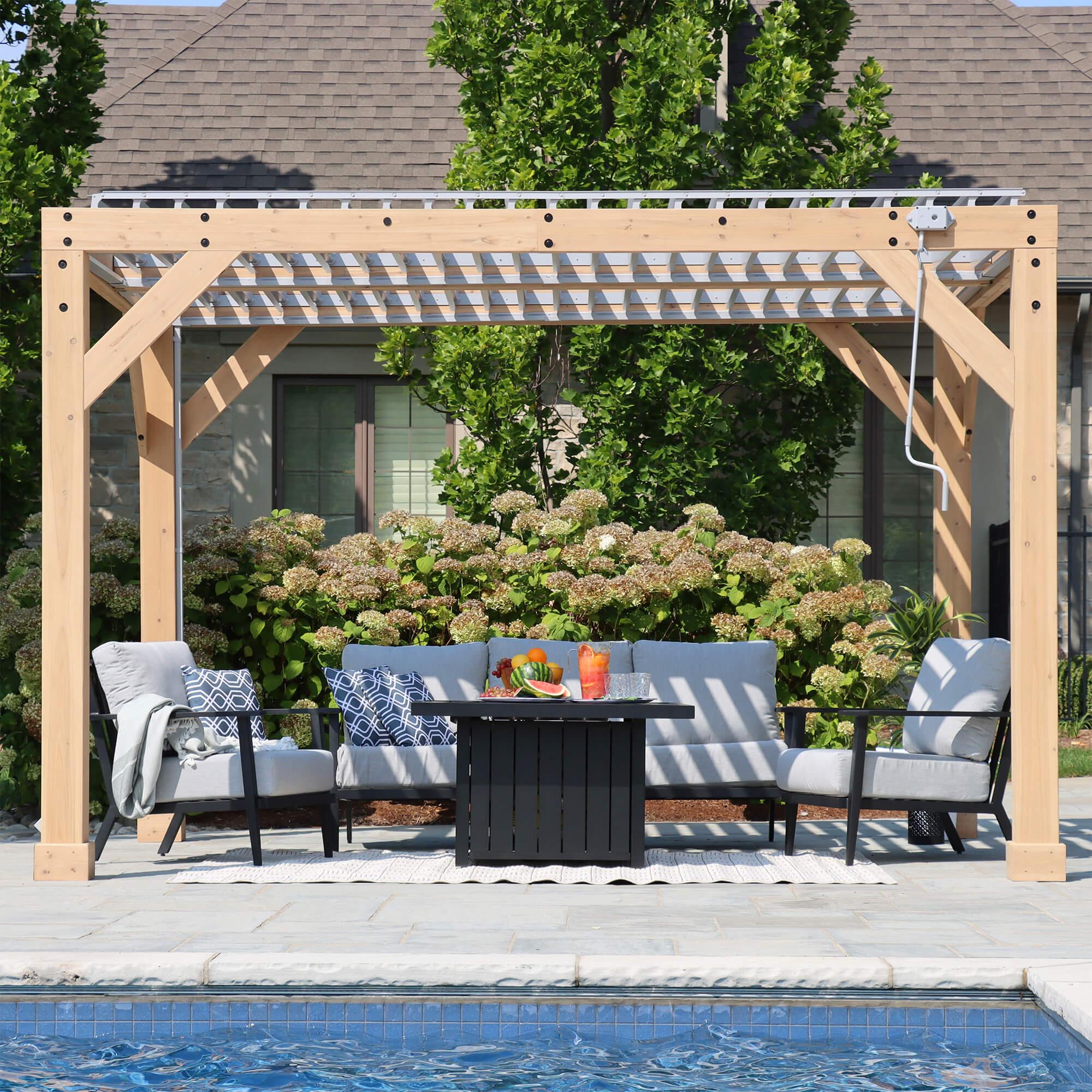 Yardistry Meridian Wooden Louvered Pergola in natural cedar beside a pool, louvers open, with the hand crank hanging from the beam
