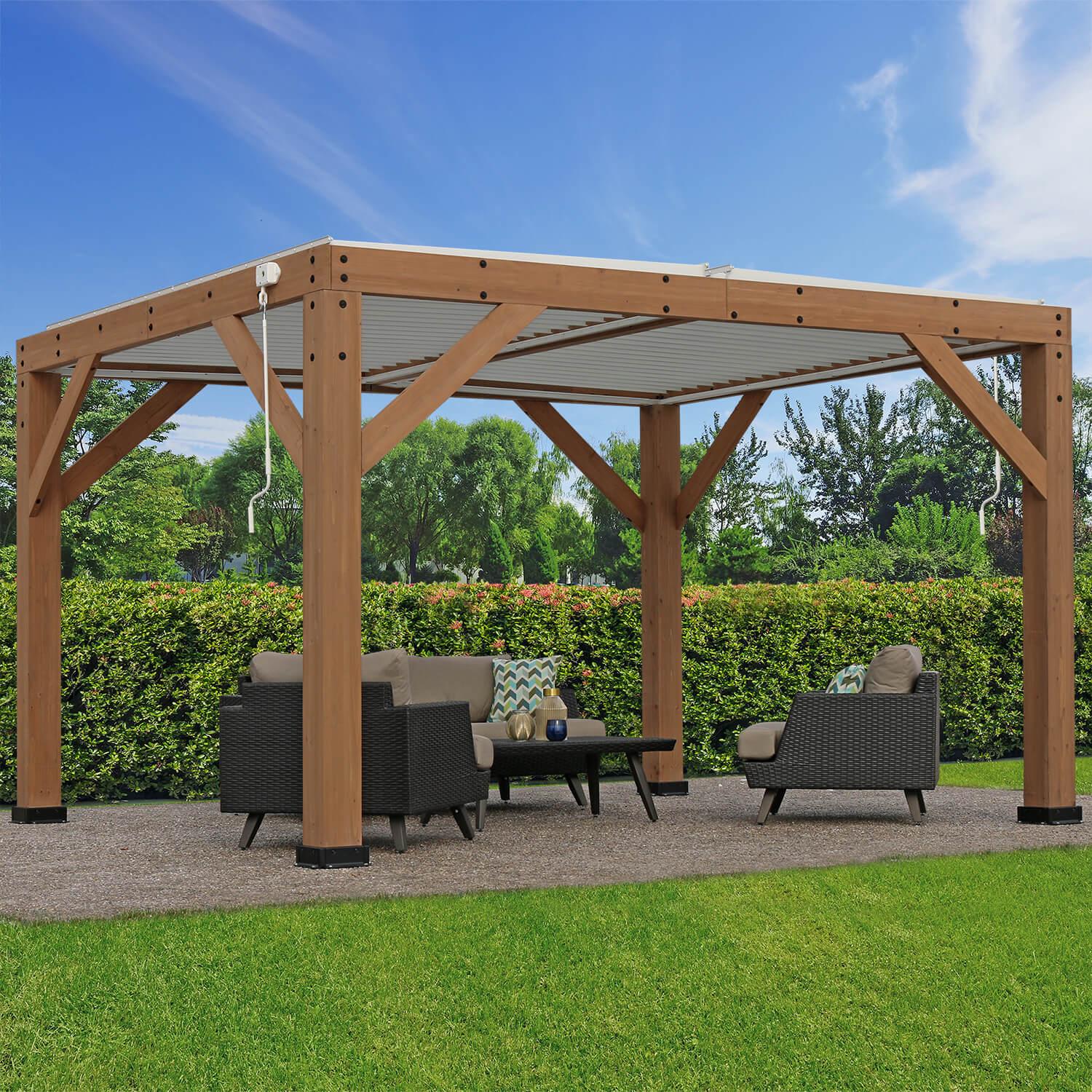 Three-quarter view of the Yardistry 13 x 11 Wood Room With Louvered Roof on a gravel patio beside a clipped hedge, louvers closed for shade